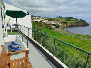 a balcony with a bench and an umbrella at Sea Bay House in Lagoa