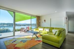 a living room with a green couch and a large window at Mapua Wharfside Apartments in Mapua