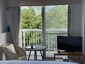 a room with a bed and a television and a table at WITH SEA Nakama in Onna