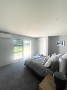 a bedroom with a large bed and a large window at Beachside Bliss - Modern Luxury in Napier