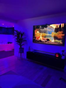 a living room with a tv on a purple wall at Wood Spa Wellness Suite mit Whirlpool & Sauna nahe Göttingen in Rosdorf