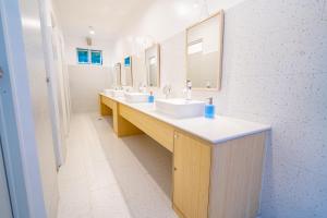 a bathroom with three sinks and two mirrors at SunDay Hostel in Siquijor