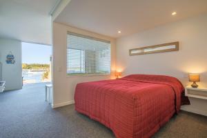 a bedroom with a red bed and a window at Mapua Wharfside Apartments in Mapua