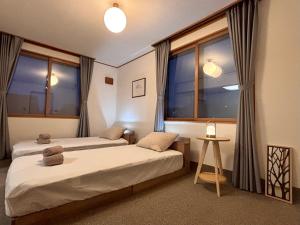 a bedroom with two beds and a large window at Snoa Kitanomine - スノア キタノミネ - in Furano