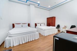 two beds in a room with white walls and wooden floors at Hotel Tri Tôn in Tri Tôn