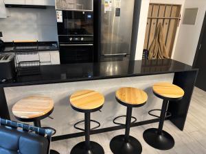 a kitchen with four wooden stools in front of a counter at Excelente, Exclusivo Depto en Pucón in Pucón