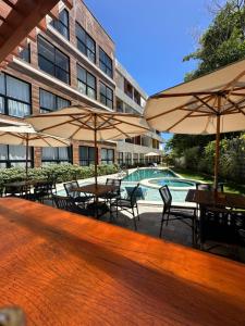 a patio with tables and umbrellas in front of a building at Maré alta flat 213 in Tamandaré