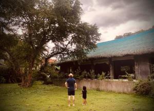 a man and a child standing in front of a house at Caba La Union Gulfside Cottage C3 in Caba