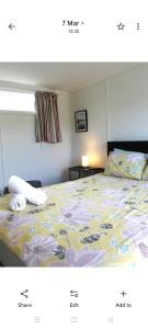 a picture of a bedroom with a bed with flowers at Raglan park rest and stay cabins - Private studio in Raglan