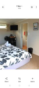 a bedroom with a bed with a black and white comforter at Raglan park rest and stay cabins - Private studio in Raglan