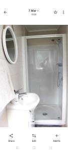 a bathroom with a shower and a sink and a mirror at Raglan park rest and stay cabins - Private studio in Raglan +8 photos