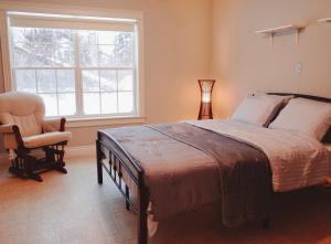 a bedroom with a bed and a chair and a window at EcoSun Hostel in Montague