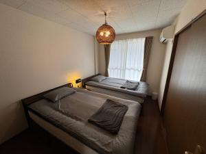 two beds in a small room with a chandelier at BreakPoint in Ichinomiya