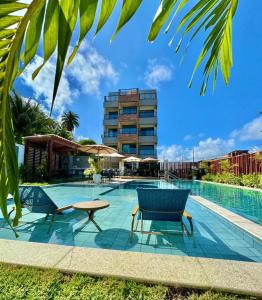 a swimming pool with two chairs and a building at Maré alta flat 213 in Tamandaré