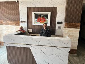 a man sitting at a counter in a lobby at Hotel Dubeyinn in Katra