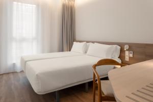 a bedroom with a large white bed and a chair at B&B HOTEL Madrid Vallecas Ensanche in Madrid +25 photos