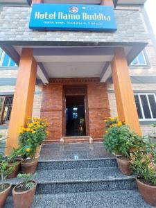 a hotel mana building with potted plants in front of it at Hotel namo buddha in Sauraha