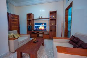 a living room with a couch and a tv at Résidence Aïcha in Rufisque