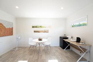 a white room with a table and chairs and paintings at Studio 17 Private Standalone Studio in Greenhithe North Shore in Auckland
