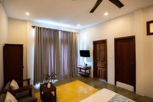 a living room with a bed and a tv and a couch at Isann Suites in Phumĭ Réach Born (1)
