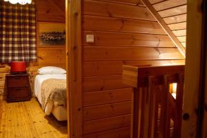 a bedroom with a bed in a log cabin at Chalé do Zêzere in Cortes do Meio +7 photos