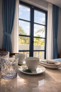 a table with bowls and plates on it with a window at Cybade Hôtel in Phú Quốc