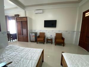 a bedroom with a bed and two chairs and a tv at Khách Sạn Ninh Thọ in Quảng Ngãi