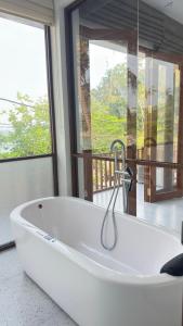 a white bath tub in a room with a window at Surf Villa Hiriketiya in Hiriketiya