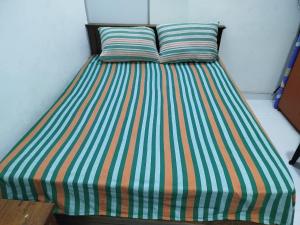 a bed with a striped bedspread and two pillows at Manjula Luxury AC Apartments in Negombo