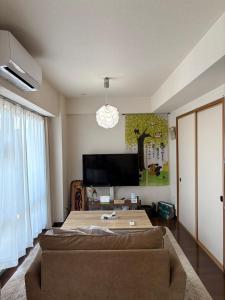 a living room with a couch and a flat screen tv at kotobuki504condotel in Imai-kamichō