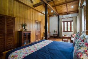 a bedroom with a blue bed and wooden walls at Isann Suites in Phumĭ Réach Born (1) +26 photos