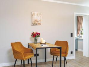 a dining room table with two chairs and a vase of flowers at Kliffsand-73 in Kampen +3 photos