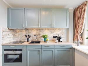 a kitchen with blue cabinets and a sink at Kliffsand-73 in Kampen