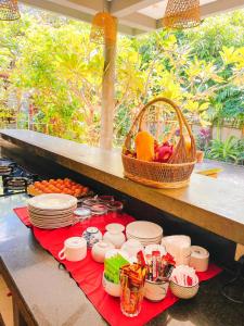 a table with plates and bowls and a basket of fruit at Isann Suites in Phumĭ Réach Born (1)