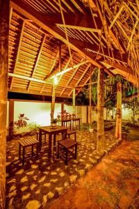 a patio with a table and benches under a roof at Eden Udawalawe in Udawalawe