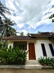 a small white house with a wooden door at Kapal Dream Homestay in Selong Belanak