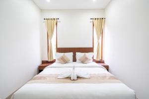 a white bed with a cross on top of it at Dekade Living in Denpasar +39 photos