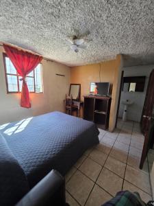 a bedroom with a bed and a desk and a window at EL MIRADOR dlr HR in Quetzaltenango