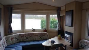 a living room with a couch and a table at Twee slaapkamer stacaravan met vissteiger in Hengelo