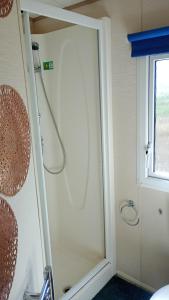 a shower with a glass door in a bathroom at Twee slaapkamer stacaravan met vissteiger in Hengelo +10 photos