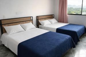 two beds with blue and white sheets in a room at Aparta Suites Torre de Prado 601 Apartamento para 9 Personas in Medellín