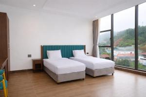 a hotel room with two beds and a large window at Ha Giang Numa Hotel in Ha Giang +31 photos
