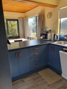 a blue kitchen with a sink and a microwave at Estuary Hideaway in Whangamata