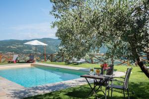 a table with flowers on it next to a swimming pool at Fienile in Pontassieve