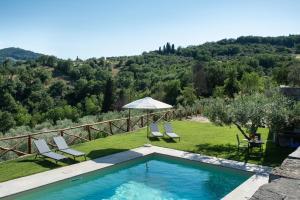 a swimming pool with two chairs and an umbrella at Fienile in Pontassieve