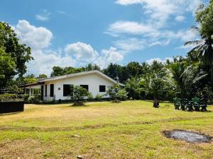 a white house with a yard and trees at Pudam Cottege in Kataragama