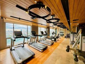 a gym with a row of treadmills and a lot of windows at Hotel Residence at Novotel in Manila