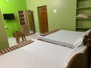 two beds in a room with green walls at abirami arulagam in Jāmb