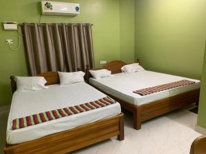 two beds sitting next to each other in a room at abirami arulagam in Jāmb