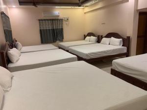 a room with three beds with white sheets at abirami arulagam in Jāmb